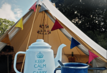Glamorous Camping: The Top Glaming Gear for Women in 2023 glamping in style with tent covered in prayer flags and a kitschy tea kettle and mug