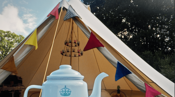 Glamorous Camping: The Top Glaming Gear for Women in 2023 glamping in style with tent covered in prayer flags and a kitschy tea kettle and mug