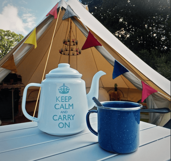glamping in style with tent covered in prayer flags and a kitschy tea kettle and mug